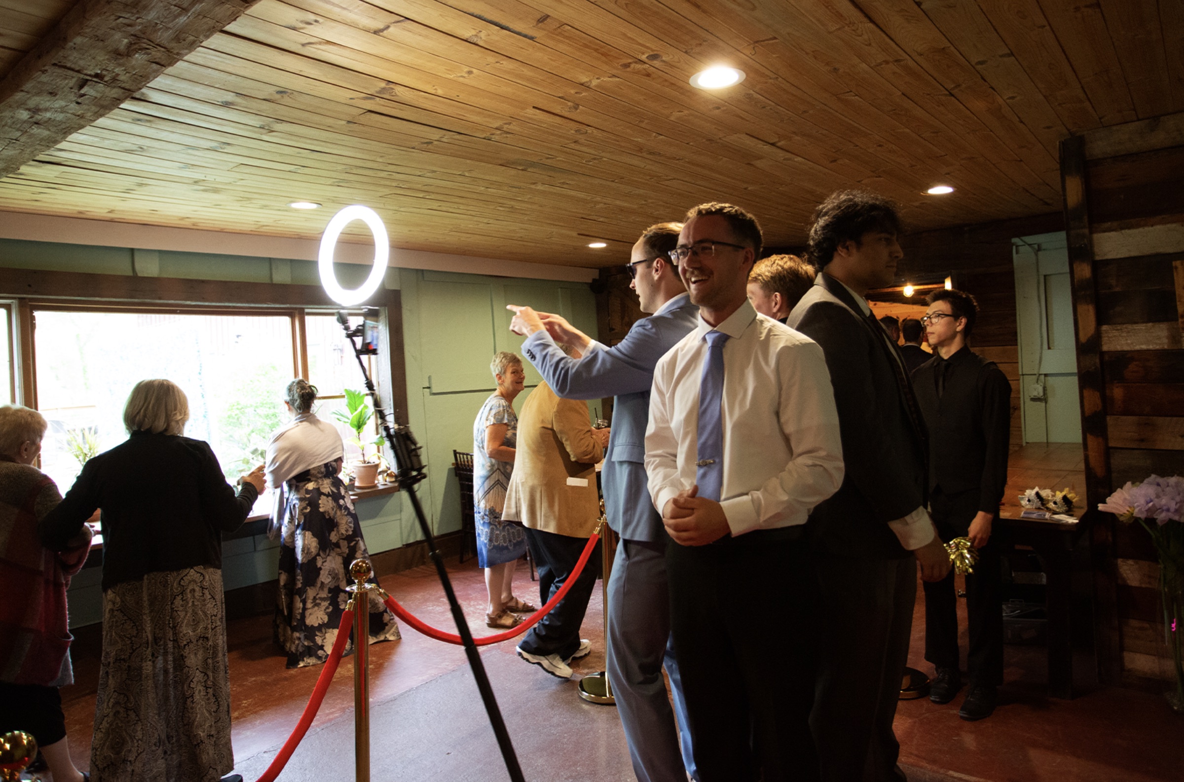Groomsmen laughing at the NextSpin 360 booth ring light at a rustic barn wedding.